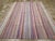 This mid-20th century Turkish flatweave Kilim rug, features a vibrant and rhythmic striped design that embodies the...