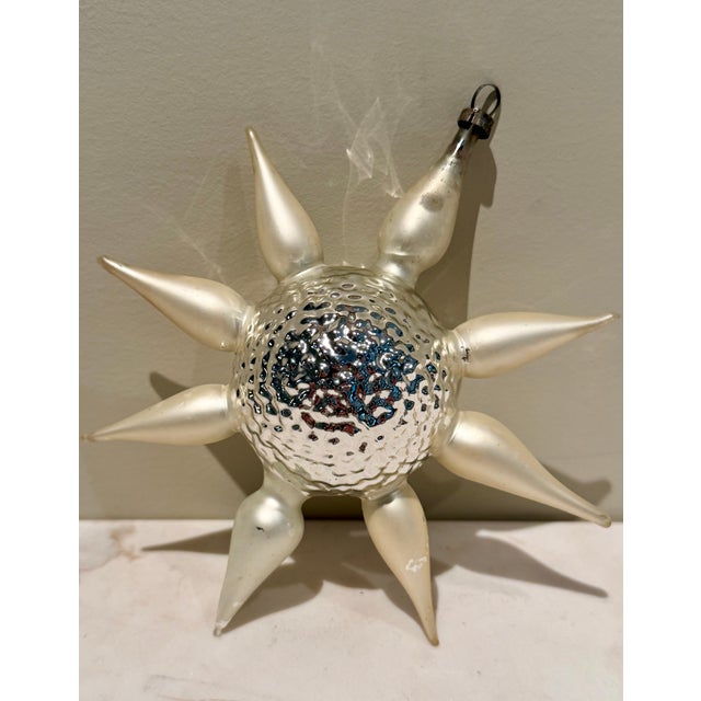 Rare German Sputnik mercury glass ornament in white and silver with colored accents. Eight white star arms feature gold,...