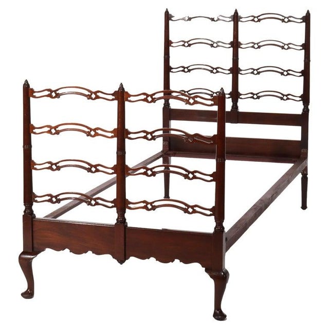 A vintage twin bed made from mahogany wood, dating back to circa 1940. The bed features intricate filigree work on the...
