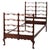 A vintage twin bed made from mahogany wood, dating back to circa 1940. The bed features intricate filigree work on the...