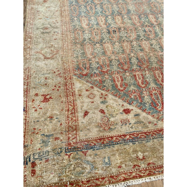 A lovely antique Malayer rug. This antique Malayer offers a muted tan palette with traditional red and blue accents.