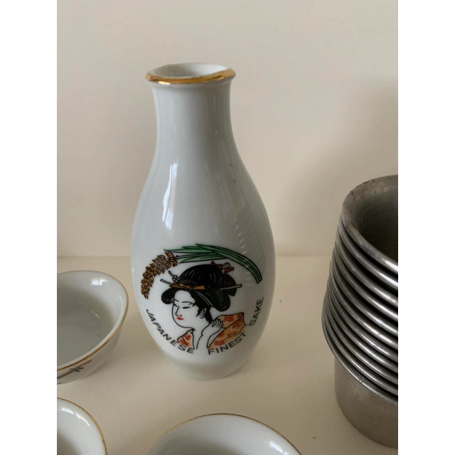 Lovely Sake Geisha Girl set of bottle and three matching ceramic cups. Comes with a set of 11 metal Sake cups marked Lion...