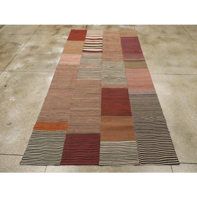 This Mid-20th century Turkish Flatweave Kilim rug, offers a bold and eclectic interpretation of traditional stripe motifs....