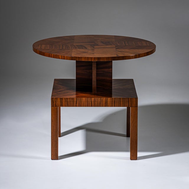 Art Deco side table in walnut with a square base raised on four legs. Above rises a cross-shaped intermediate column,...