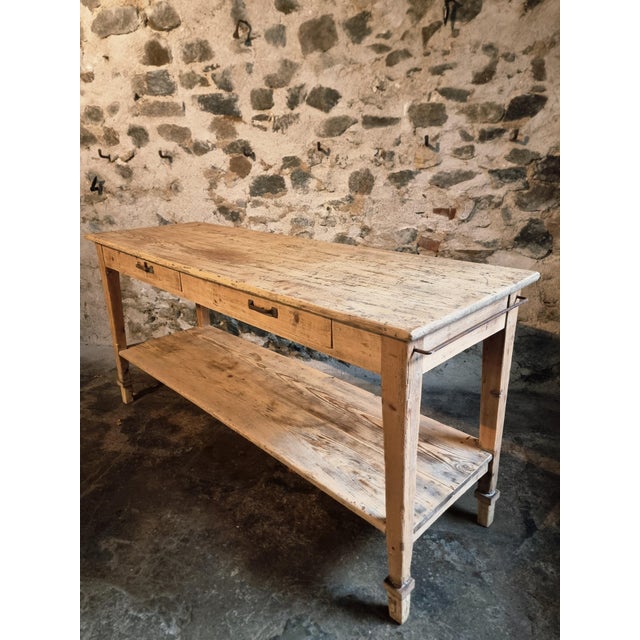A solid pine draper’s table from France, dating from around 1900. This early 20th-century worktable features two drawers...