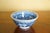 A small Chinese blue-and-white porcelain bowl featuring dense floral scroll decoration in deep cobalt blue against a white...