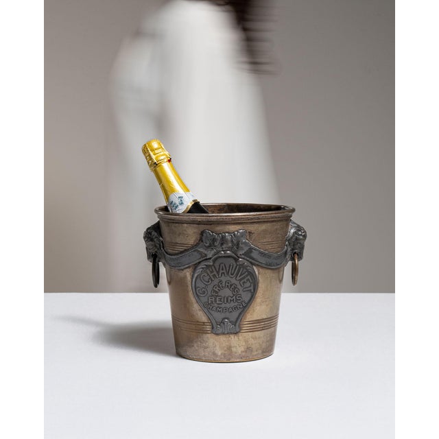 This early 20th century ice bucket from France is finished in silver. It is fitted with an ornate cast medallion crest, a...