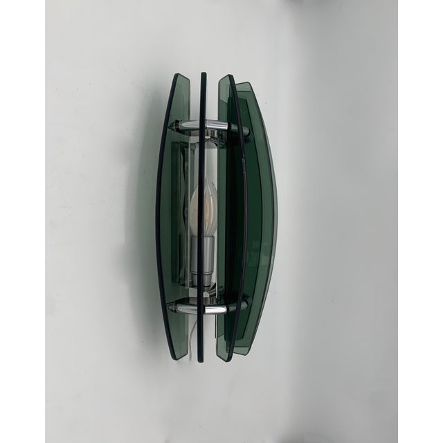 These are two designer wall lamps with a central chrome-plated metal frame and thick, dark green glass sides, a typical...