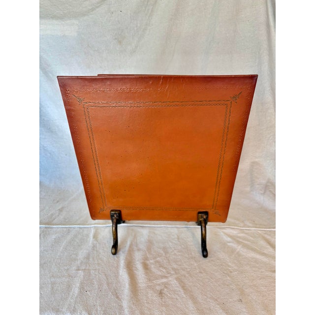 This 20th Century Leather and Cast Iron Magazine Rack dates back to the mid 1900's. The piece features a tooled brown...