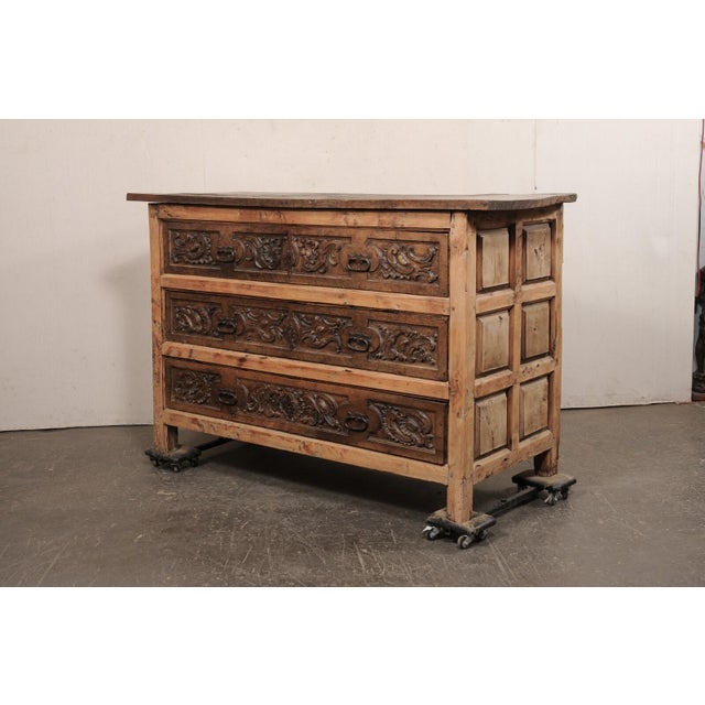 An Italian Baroque large-sized, two-toned, chest of three drawers, with ornately carved drawer fronts, from the early 18th...