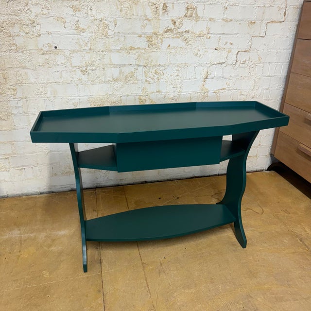 The Lozere Console Table brings sculptural elegance and functional design together in a striking emerald green lacquer...