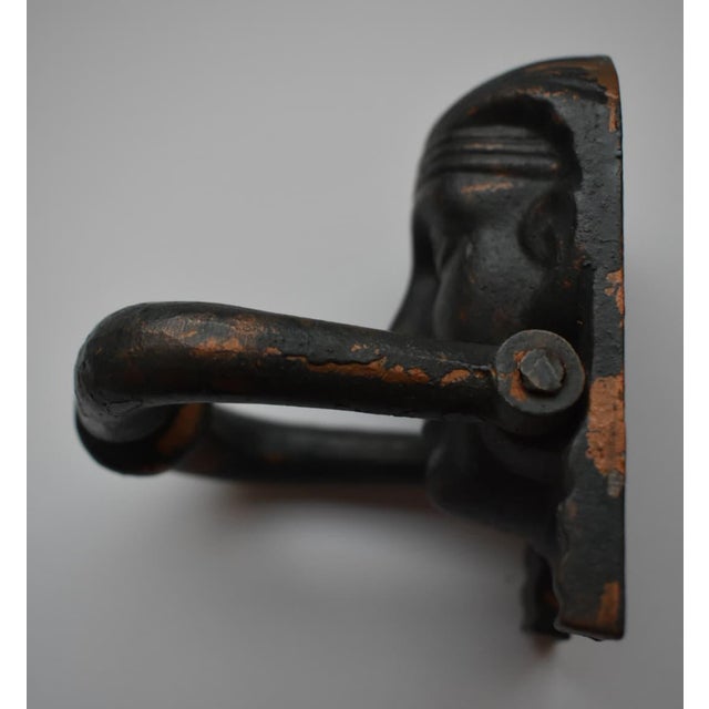 Cast Iron Egyptian Motif Door Knocker Circa 1930. The patina is a mix of dark gray with bronze colored highlights.
