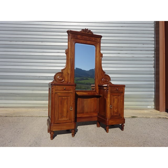 A solid walnut dressing table in the Louis XVI style. It features a large, rounded mirror with beveled edges at the top...