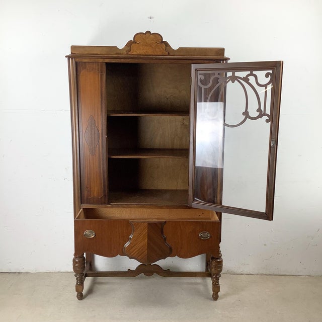 This early 20th-century display cabinet reflects traditional French provincial style furniture design adapted for domestic...