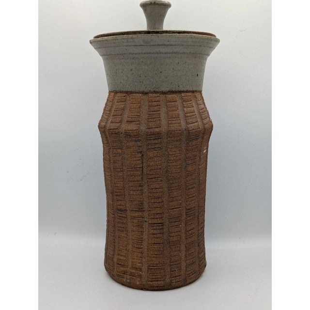 The product is a vintage Mid-Century Modern style ribbed ceramic vase with a lid, signed by the artist. This two-tone vase...