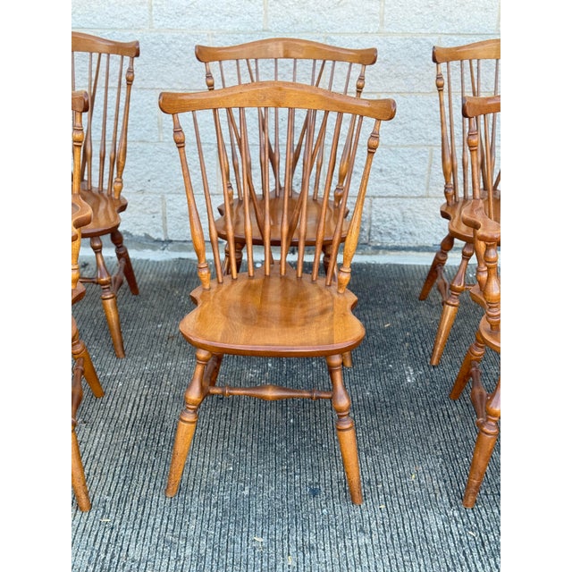 Set of six Windsor-style dining chairs in oak, each with a shaped seat, spindle back, and curved top rail. Frames...