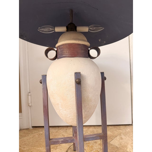 Channeling the bold architectural energy of 1980s postmodern design, this striking table lamp is created in the...