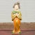 A small Chinese vintage statue of a court lady dressed in an "egg and spinach" patterned kimono and holding a small dog....