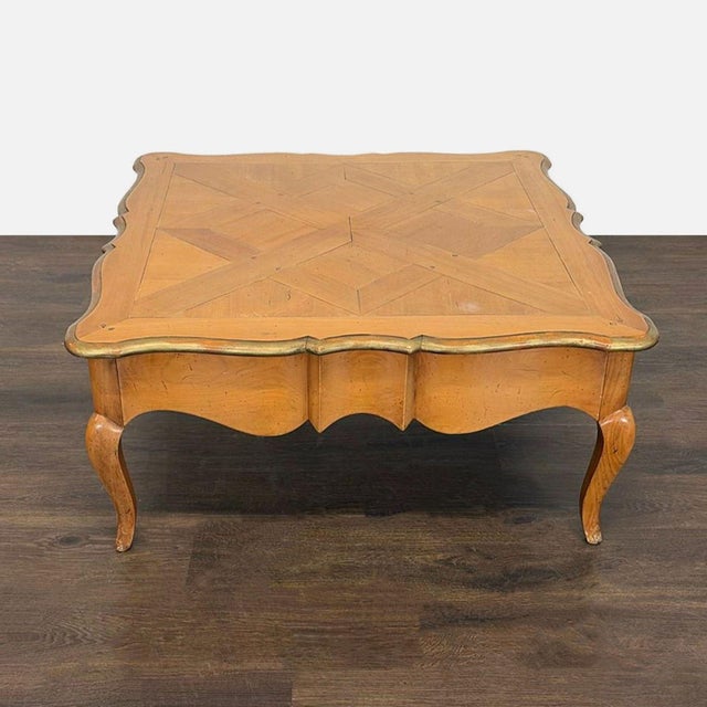 This classic wooden coffee table features a parquet-style top and elegant curved legs. It has a hidden drawer for extra...