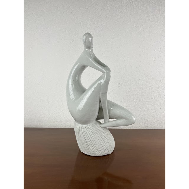 An elegant modernist ceramic sculpture depicting a stylized female figure in a meditative pose, made in Italy in the...