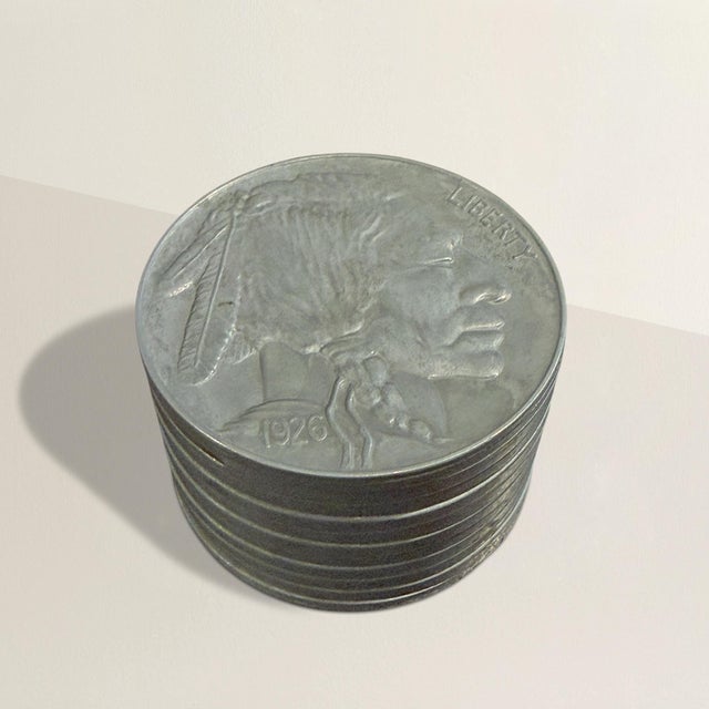 An oversized stack of Buffalo Nickels, cast in solid zinc, cool to the touch and satisfyingly weighty in the hand....