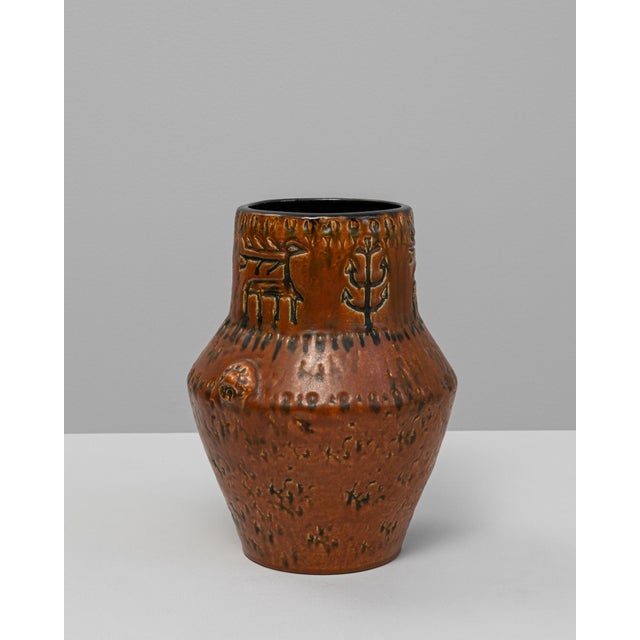 20th Century German Ceramic Vase. This expressive vase features a rich burnt sienna glaze with embossed motifs and...