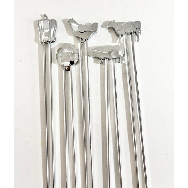A whimsical set of five vintage stainless steel cocktail picks topped with miniature figural motifs including a cow, pig,...