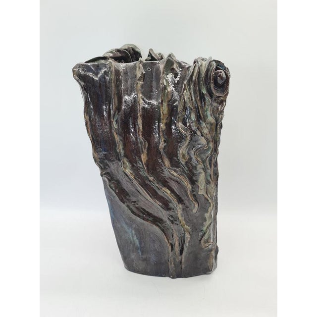 A unique, handcrafted ceramic vase with an expressive, organic form inspired by nature. The body is adorned with fluid,...
