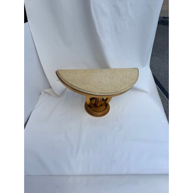 French Louis XVI-style half moon side table featuring a marble top, gold finish, and fluted columns. The gold is hand...
