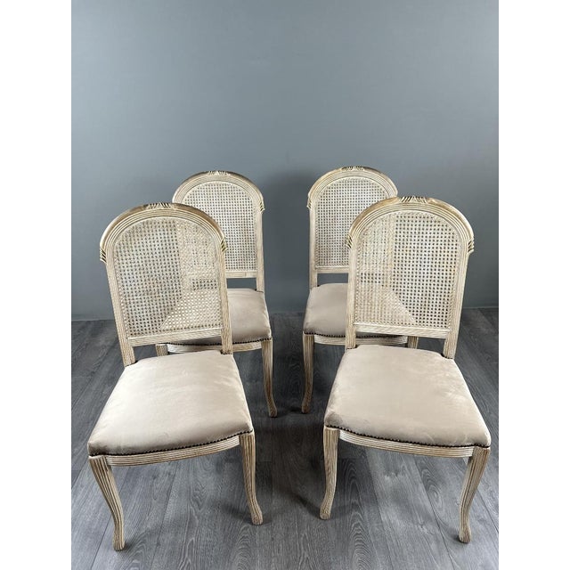 Set of four chairs in molded and carved wood, resting on fluted, tapered legs. The backs are caned, and the seats are...