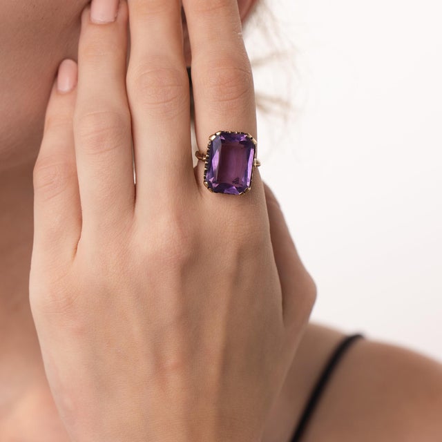 This striking vintage amethyst ring is a colorful 1970’s design, centered by an emerald cut amethyst weighing...