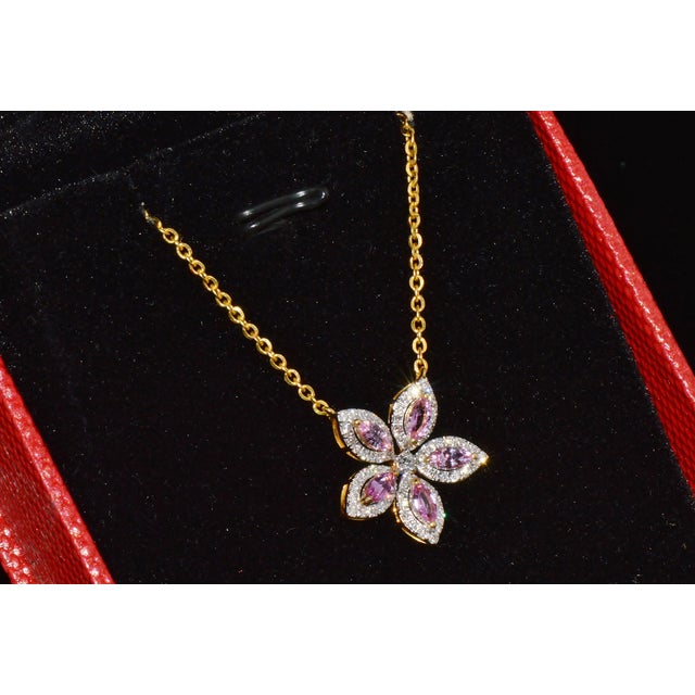 This elegant natural pink sapphire and diamond floral necklace is crafted in solid 18K yellow gold. The timeless floral...