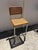 Striking vintage bar stool featuring a tubular chrome cantilever frame with warm-toned wood trim and woven cane panels on...