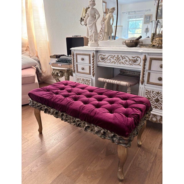 An elegant antique carved giltwood bench featuring an ornate scrolling foliate frame and gracefully curved cabriole legs,...