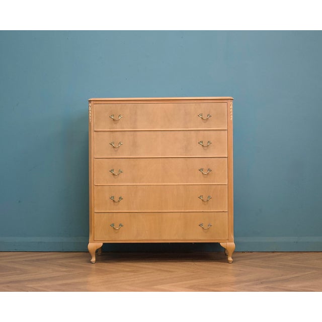 A mid 20th century chest of drawers in a light limed finish, with a shaped front and cabriole legs. French-inspired in...