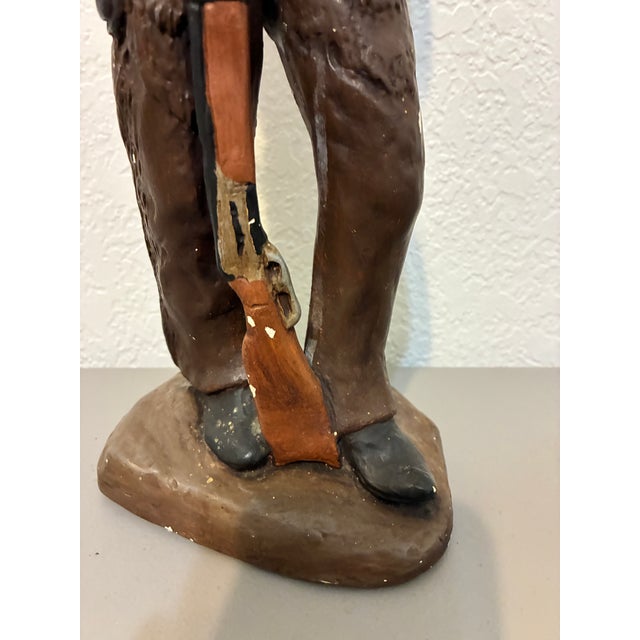 Vintage cowboy figurine statue with hand-painted finish, depicting a standing western figure holding a rifle. This rustic...