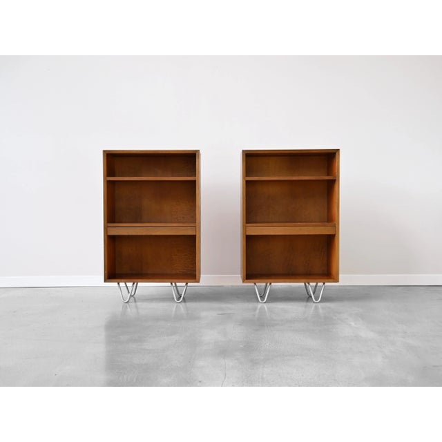 Pair of bookcases in walnut with slide-out shelves and signature aluminum hairpin legs designed by George Nelson for...