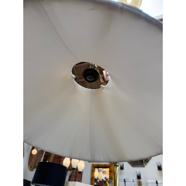 Elegant vintage floor lamp featuring a polished brass frame, a gracefully curved swivel arm, and a white pleated fabric...