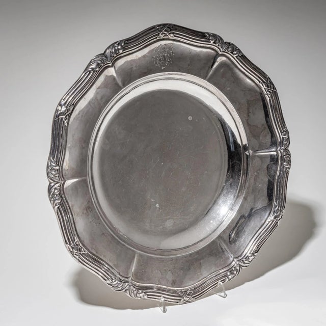 Impressive large silver plate with a scalloped rim and fluted border, decorated with neoclassical leaf and ribbon motifs....