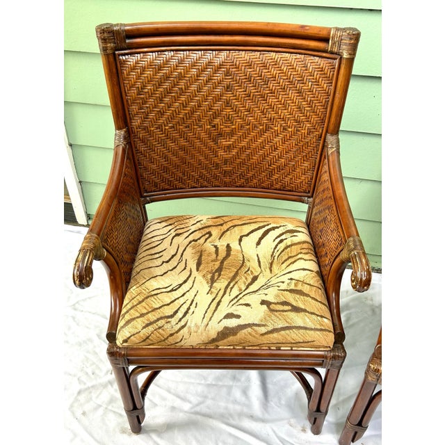A striking pair of vintage rattan accent chairs combining warm tortoiseshell-toned bamboo, intricately woven backs, and...
