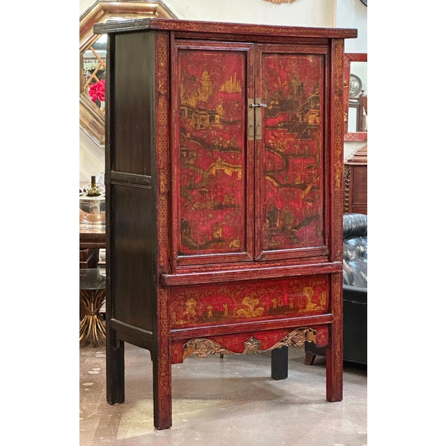 A fine Chinoiserie red lacquered cabinet or armoire from the early 20th century, featuring a moulded top over a frieze of...