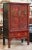 A fine Chinoiserie red lacquered cabinet or armoire from the early 20th century, featuring a moulded top over a frieze of...