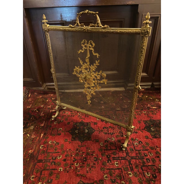 Elegant antique French brass fireplace screen dating to the early 20th century, featuring an ornate decorative design with...