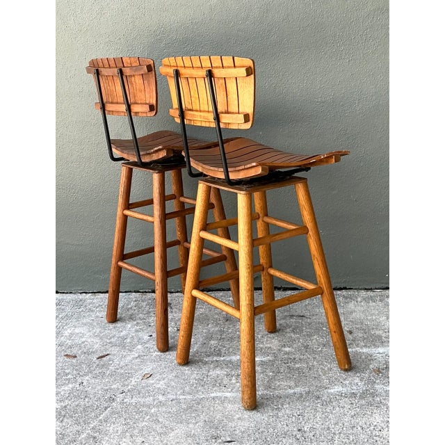 Designed in the distinct utilitarian manner of Arthur Umanoff, this pair of mid-century modern bar stools combines warm...