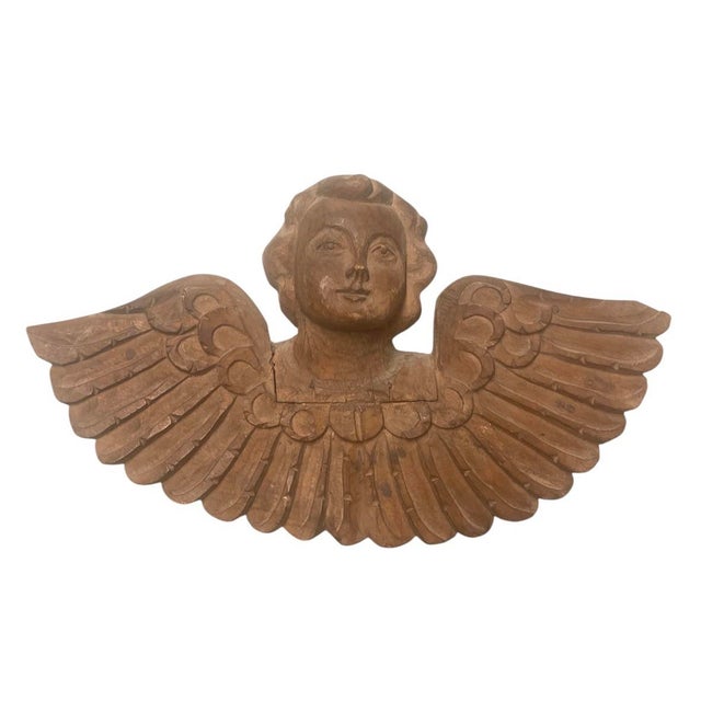 This striking, hand-carved wooden architectural element depicts a winged cherub or seraph, rendered with exceptional depth...