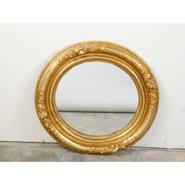 An English giltwood round mirror from the 19th century, with carved flowers and etched motifs. Created in England during...