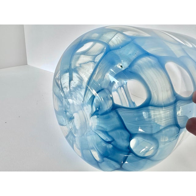 A captivating piece of contemporary blown glass, this vase features a mesmerizing web of translucent blue that ripples...