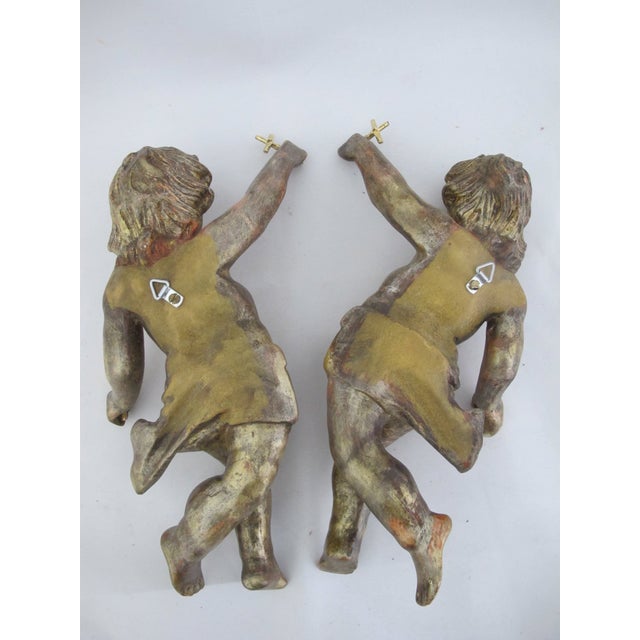Vintage pair of carved, gilded wooden angel figures, or putti, each with outstretched arms holding a cross and a sphere....