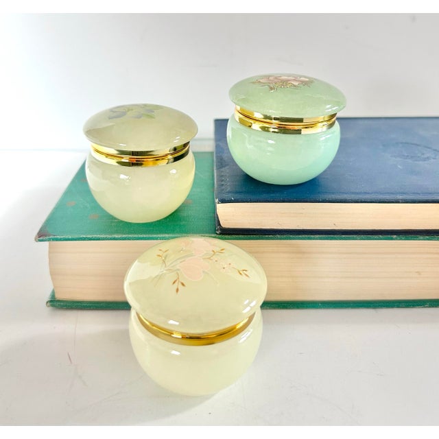 A charming set of three vintage Italian alabaster trinket boxes featuring delicate hand-painted floral motifs, perfect for...