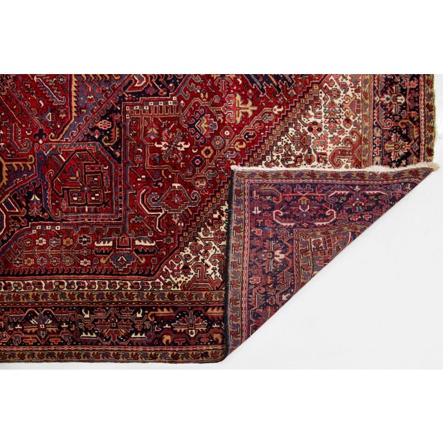 Experience the timeless elegance of this stunning vintage Persian Heriz rug, showcasing a vibrant red field. At its heart...